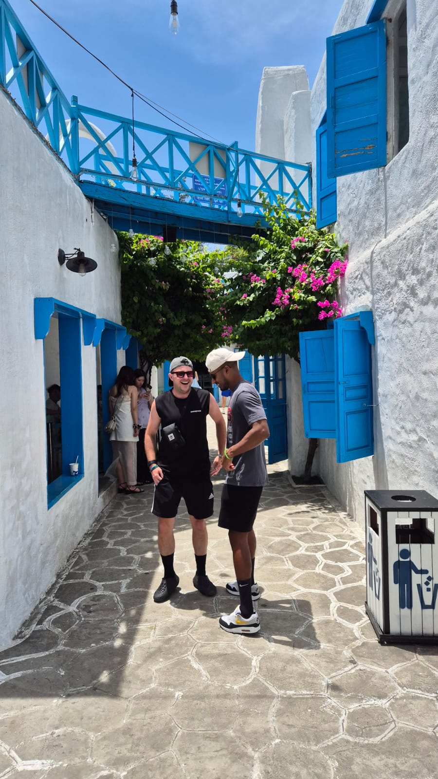 The two founders laughing together in a blue-and-white alleyway — from their own travel photos